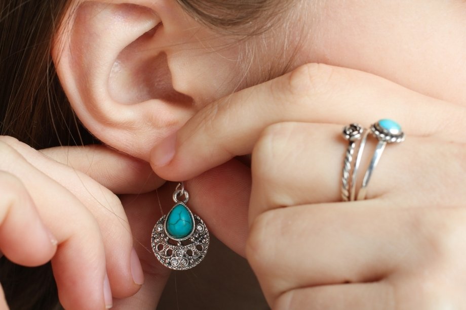 Close-up of a collector putting on a hand-wrought Native American sterling silver earring.