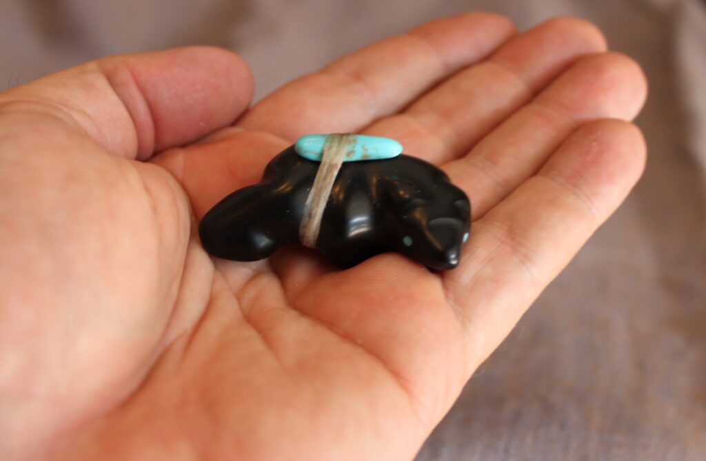 A hand-carved Zuni black bear stone fetish gift featuring an inlaid turquoise bundle.